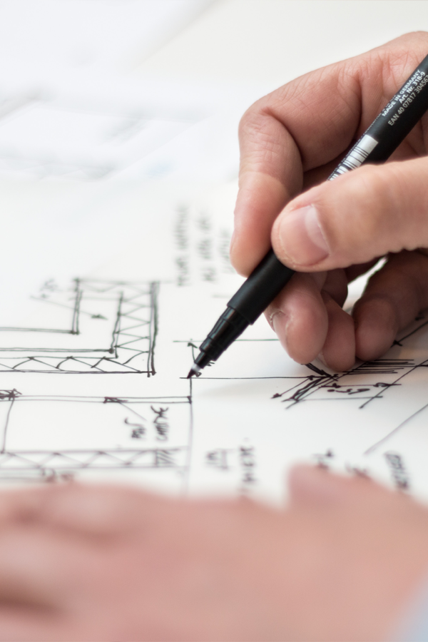 close up of a person drawing graphs or building outlines on paper with a black pen